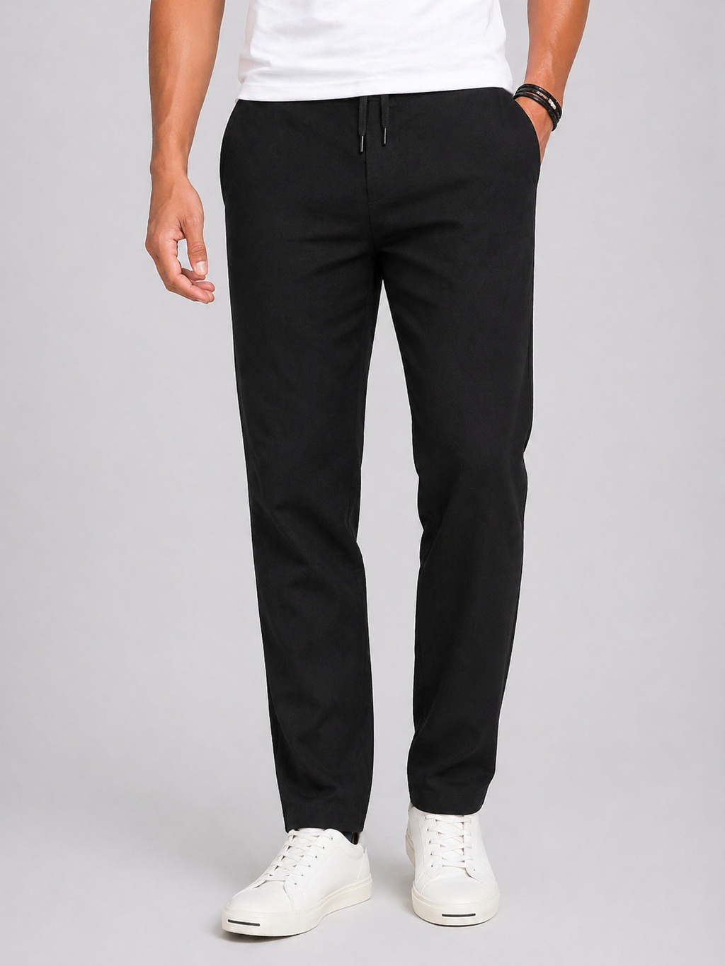 Men's black lightweight linen drawstring pants with a tapered leg and side pockets, paired with white sneakers.