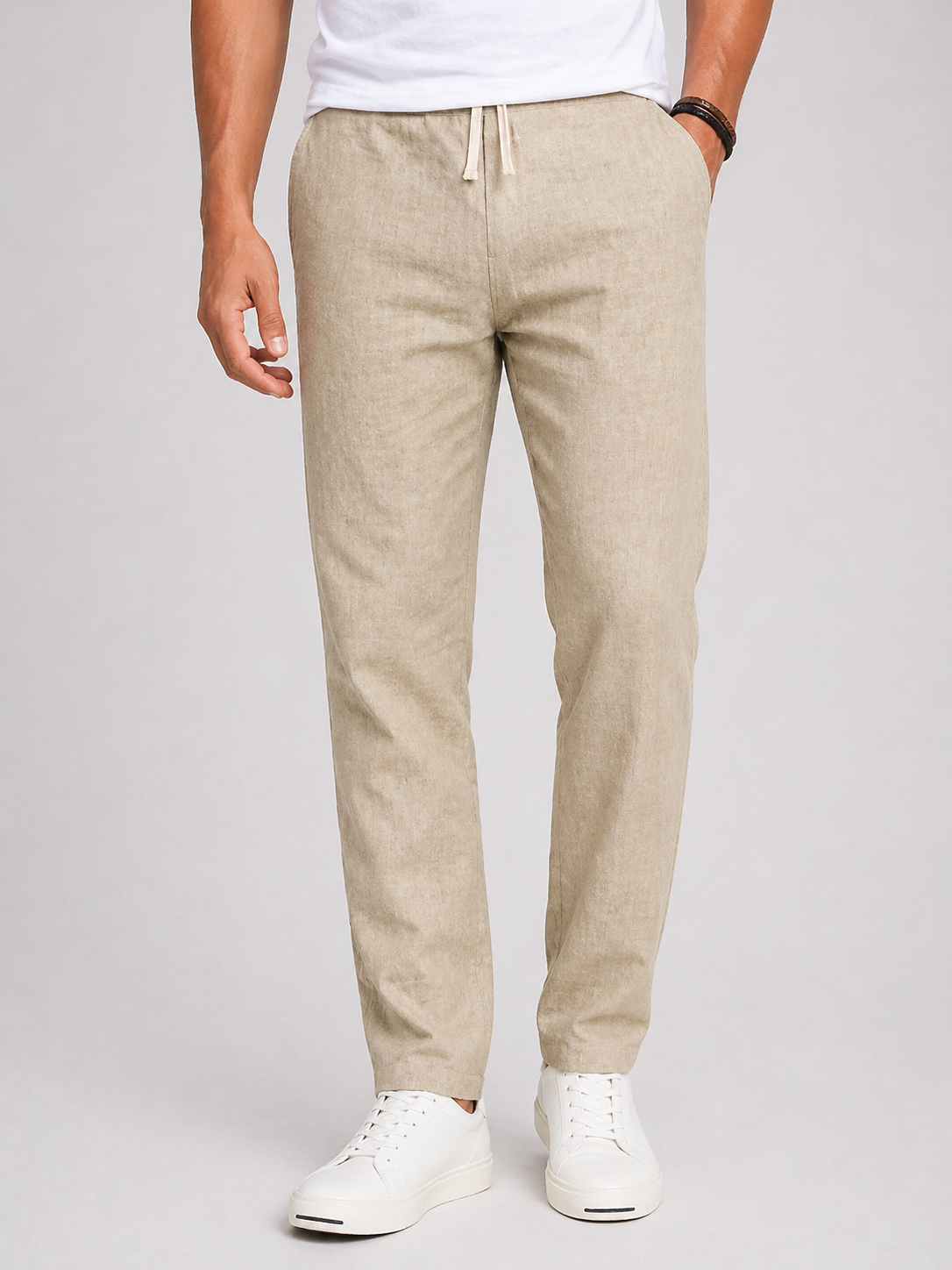 Men's beige lightweight linen drawstring pants with tapered leg, side pockets, and natural texture.
