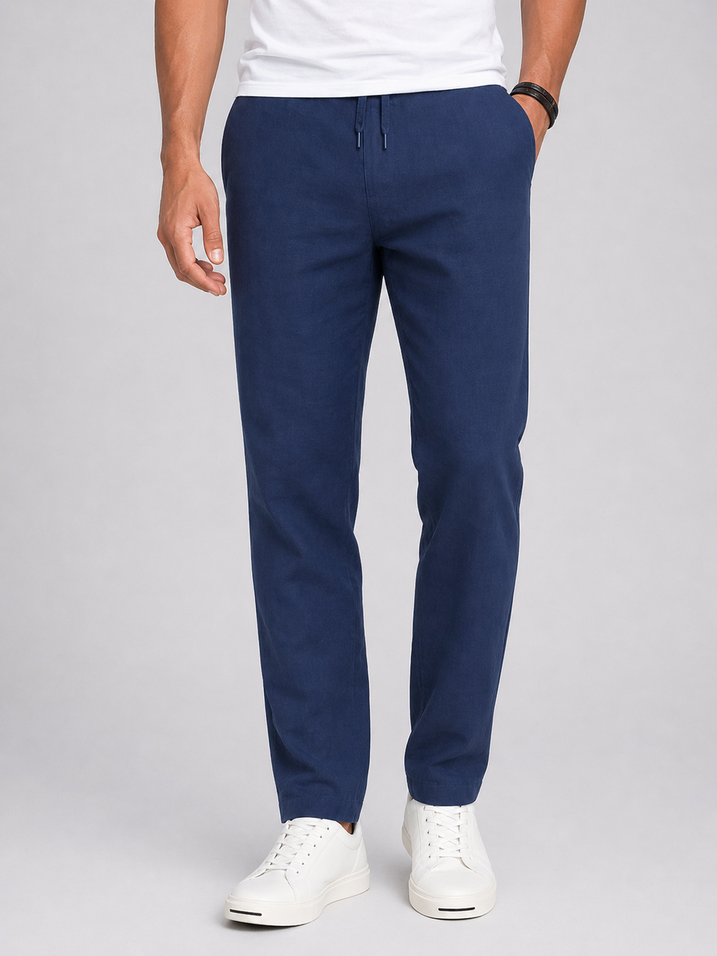 Person wearing navy blue pants and white sneakers on a light gray background