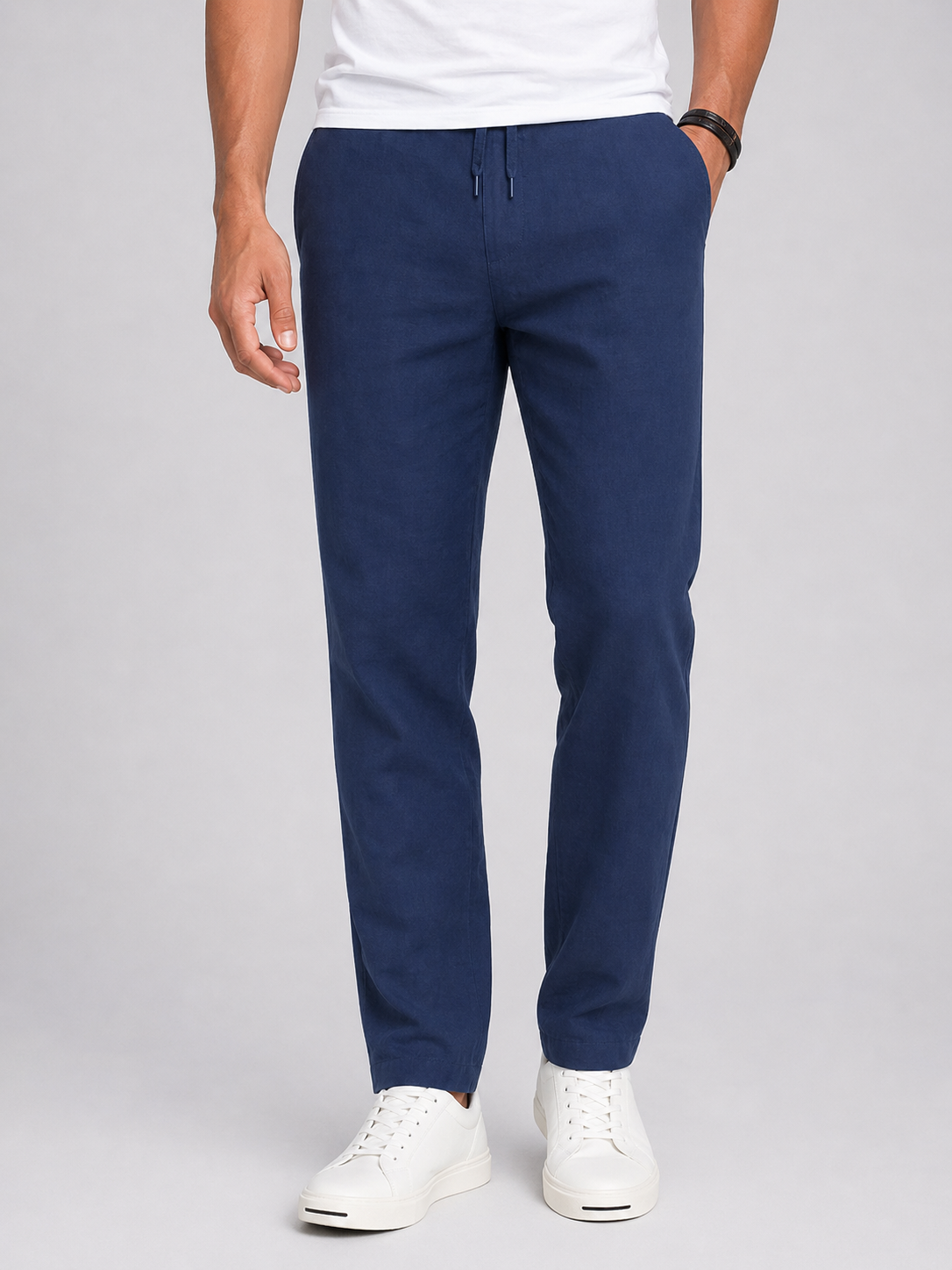 Person wearing navy blue pants and white sneakers on a light gray background