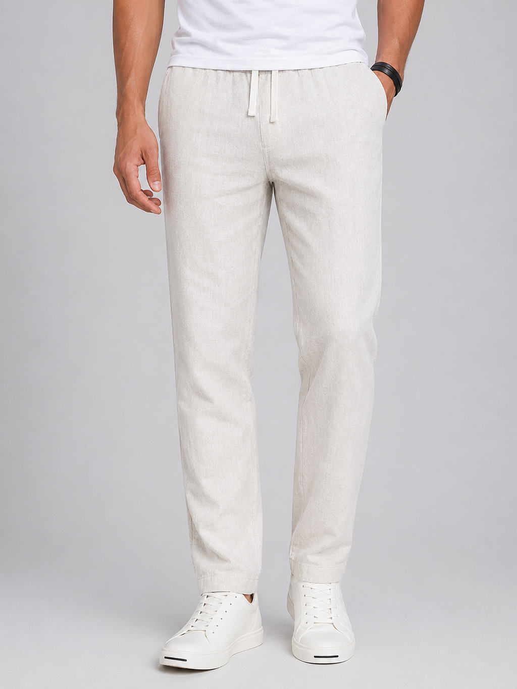 Men's light beige linen drawstring pants with a tapered leg and side pockets, paired with white sneakers.