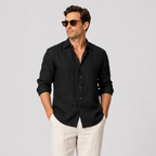 Men's black linen long sleeve button-up shirt with an open collar, paired with light linen trousers.