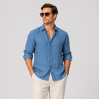 Men's blue linen long sleeve button-up shirt with an open collar, paired with light linen trousers.