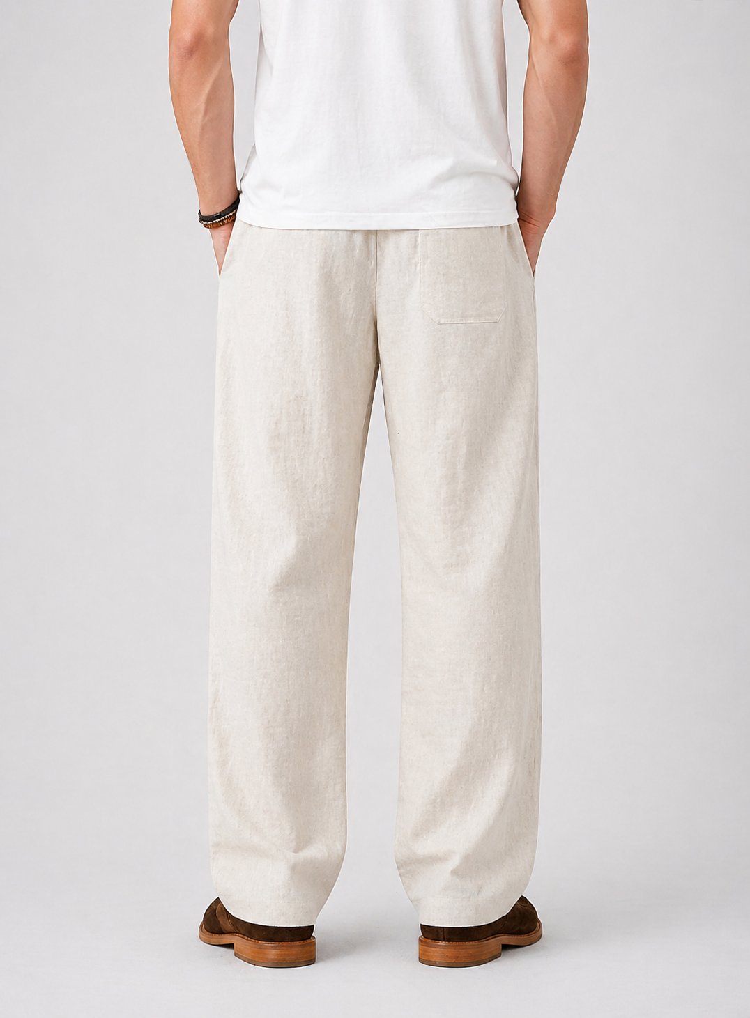 Men's beige wide-leg linen pants with drawstring waist and back pocket, worn with a white t-shirt.