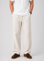Men's natural linen wide-leg drawstring pants with side pockets, paired with a white t-shirt and brown loafers.