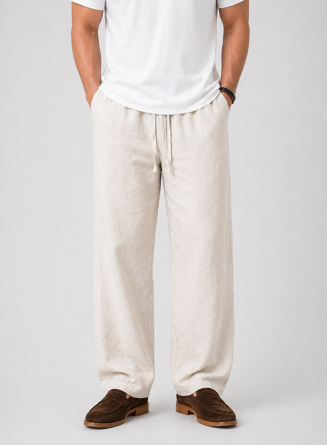 Men's natural linen wide-leg drawstring pants with side pockets, paired with a white t-shirt and brown loafers.