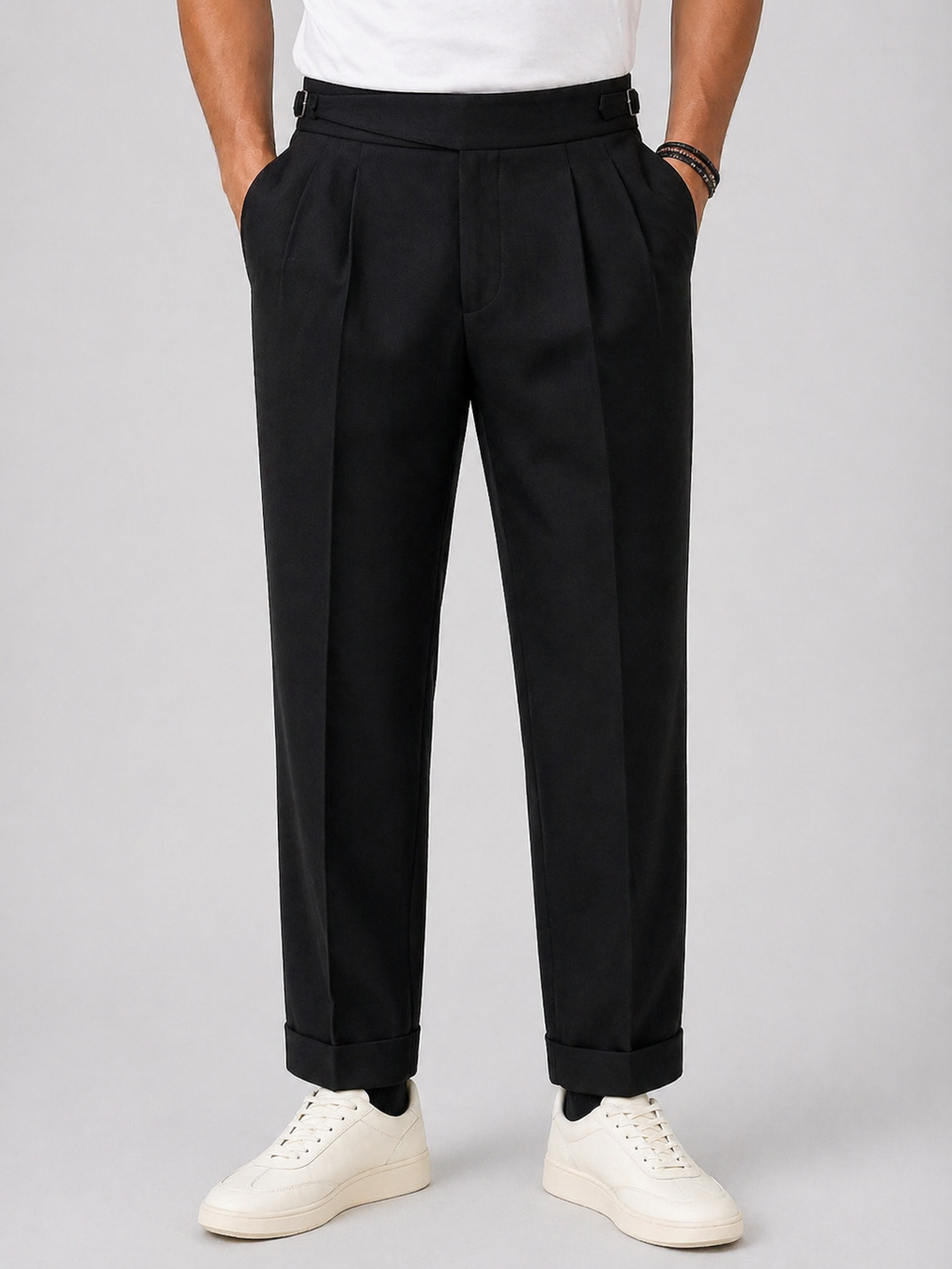 Men's black relaxed twin-pleat high-waist pants with side adjusters and cuffed hems.