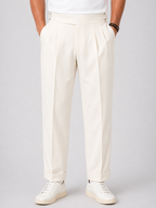 Men's relaxed fit, high-waist twin-pleat pants in cream, with side adjusters and cuffed hems.