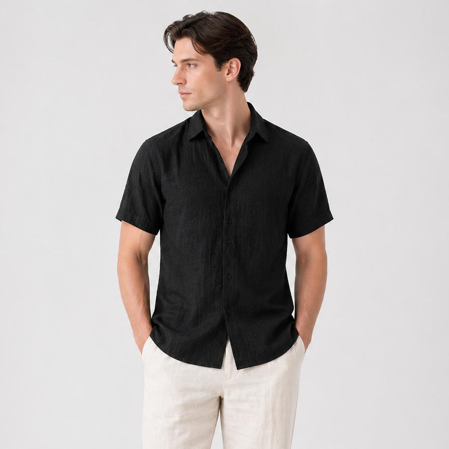 Men's black short sleeve button-up shirt with a classic collar, paired with light beige linen pants.