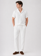 Man wearing a white outfit with brown shoes on a light gray background